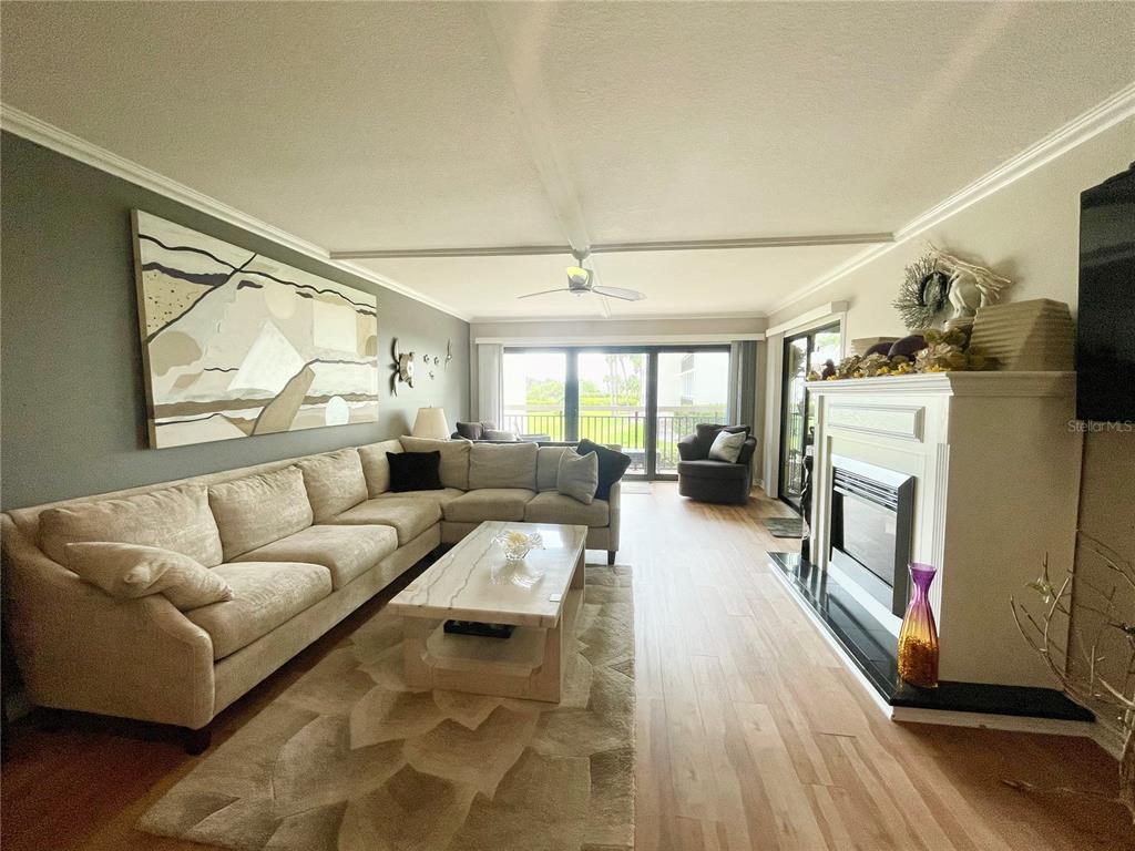 A living room features a large sectional sofa, a fireplace, and sliding glass doors — 7893 SAILBOAT KEY BOULEVARD S UNIT 101, SOUTH PASADENA, FL