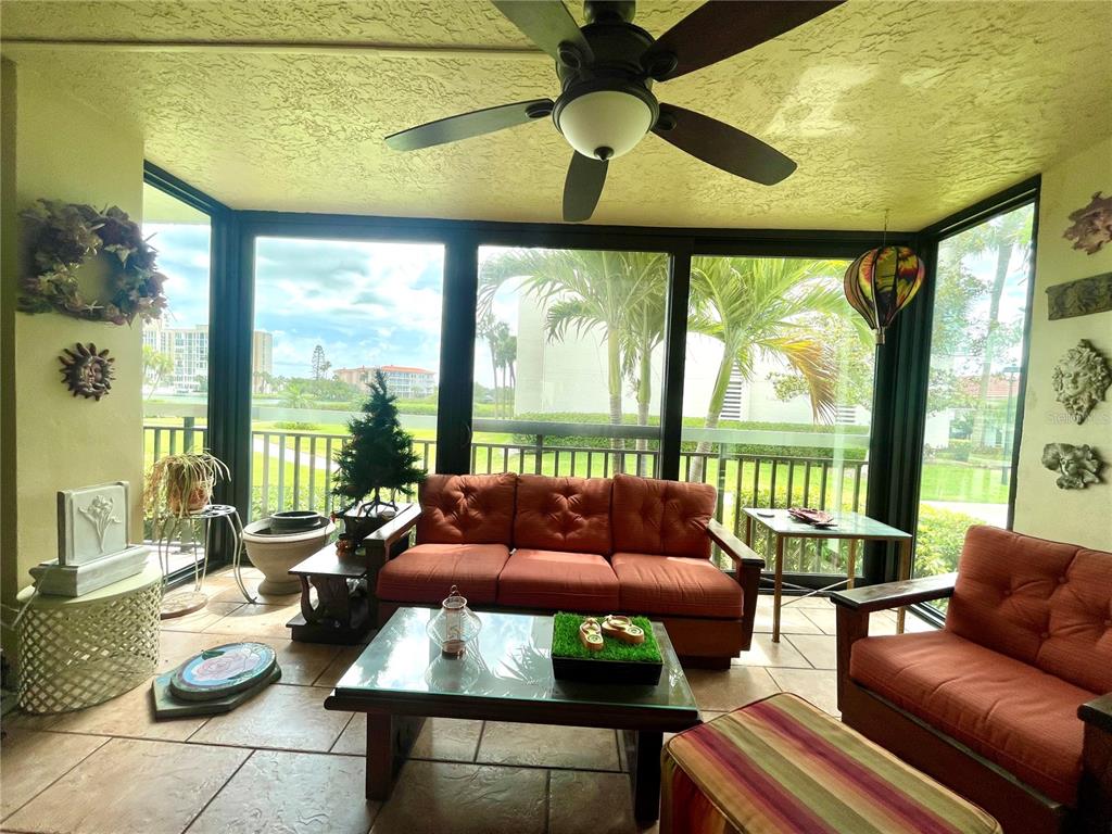 A screened-in porch features tile flooring, a ceiling fan, and views of a lake — 7893 SAILBOAT KEY BOULEVARD S UNIT 101, SOUTH PASADENA, FL