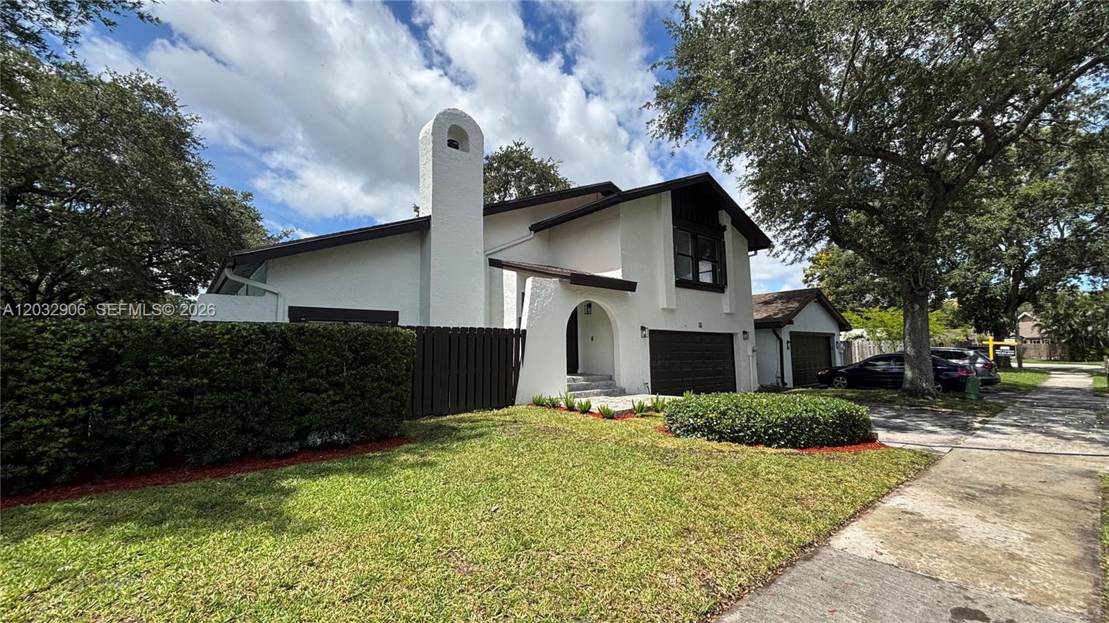 A white two-story house with a dark brown garage door and a prominent chimney — 49 Forest Cir, Cooper City FL 33026, COOPER CITY, FL