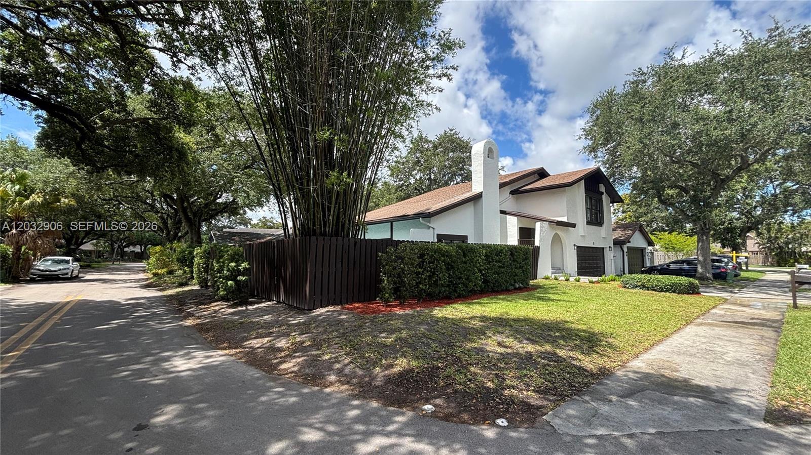 A white two-story house with a brown roof and a tall bamboo cluster behind fencing — 49 Forest Cir, Cooper City FL 33026, COOPER CITY, FL