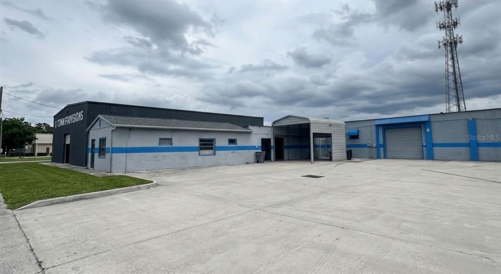 A grey commercial building with a blue stripe and a large concrete parking lot — 4120 ROUSH AVENUE, ORLANDO, FL