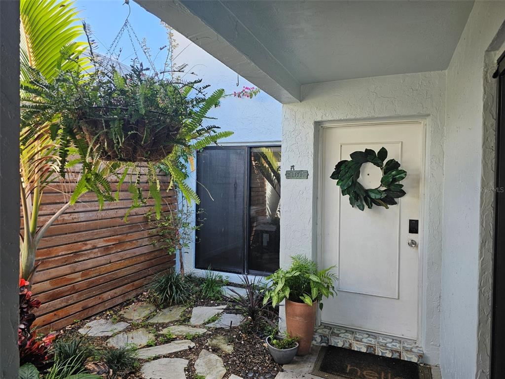 A front entryway features a stone path, a hanging plant, and a white door — 6147 43RD STREET W, BRADENTON, FL