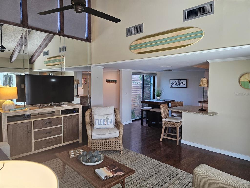 A living room features a television console, wicker chair, and a surfboard wall decoration — 6147 43RD STREET W, BRADENTON, FL
