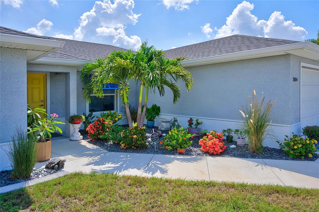 An open-concept living room and kitchen feature light wood flooring, a sectional sofa, and cabinetry — 3104 SEAFARER DRIVE, PUNTA GORDA, FL