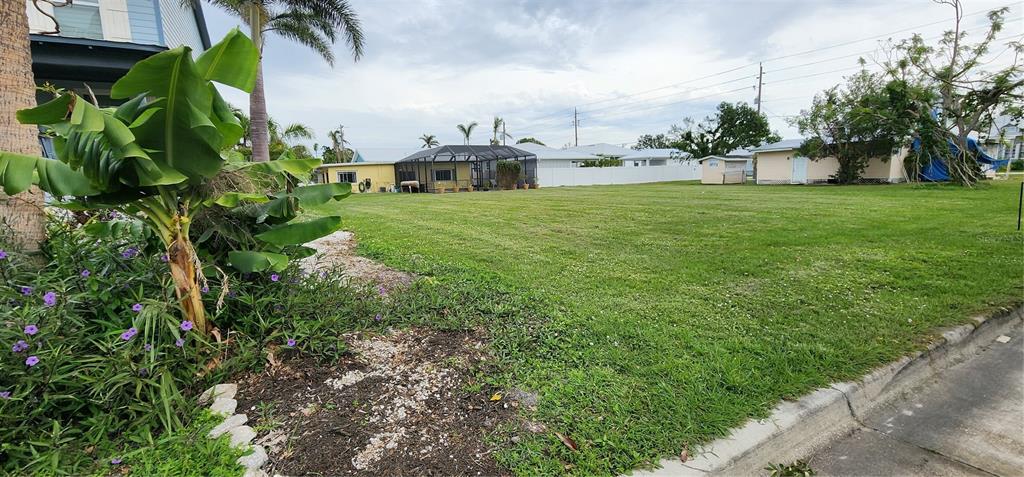 A large, grassy vacant lot is bordered by a banana plant and neighboring residential houses — 316 DURRANCE STREET, PUNTA GORDA, FL