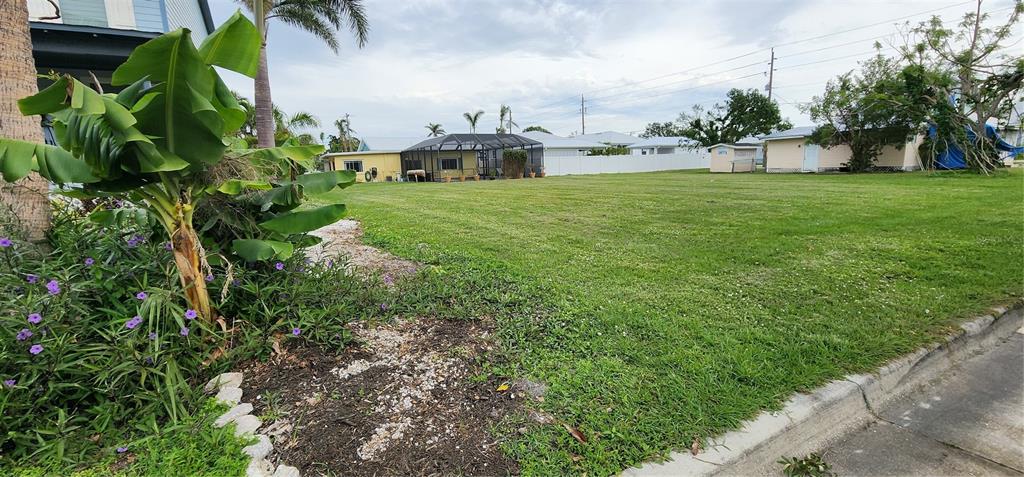 A grassy vacant lot sits between residential houses with a banana plant in the foreground — 316 DURRANCE STREET, PUNTA GORDA, FL