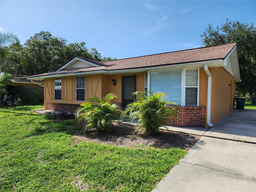 A single-story house with yellow stucco walls, a brick base, and a concrete driveway — 1225 ARMSDALE AVENUE, PORT CHARLOTTE, FL