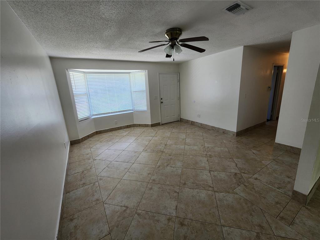 A room with beige tile flooring, a ceiling fan, and a bay window — 1225 ARMSDALE AVENUE, PORT CHARLOTTE, FL