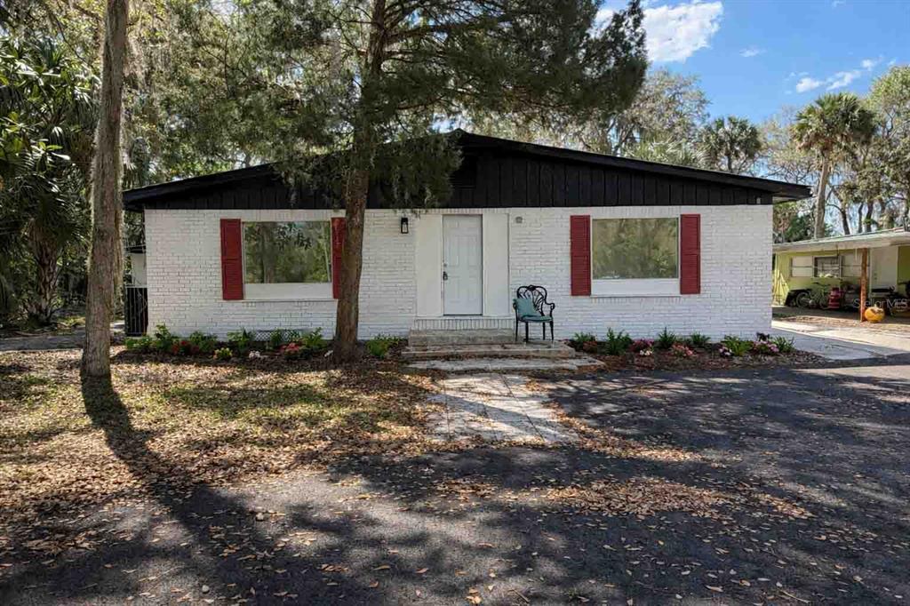 A single-story white brick house with a dark roof, red shutters, and a paved driveway — 502 NW CRYSTAL STREET, CRYSTAL RIVER, FL