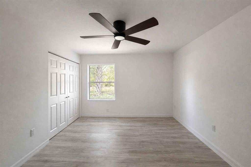 A bedroom with white walls, light wood-look flooring, a ceiling fan, and a closet — 502 NW CRYSTAL STREET, CRYSTAL RIVER, FL