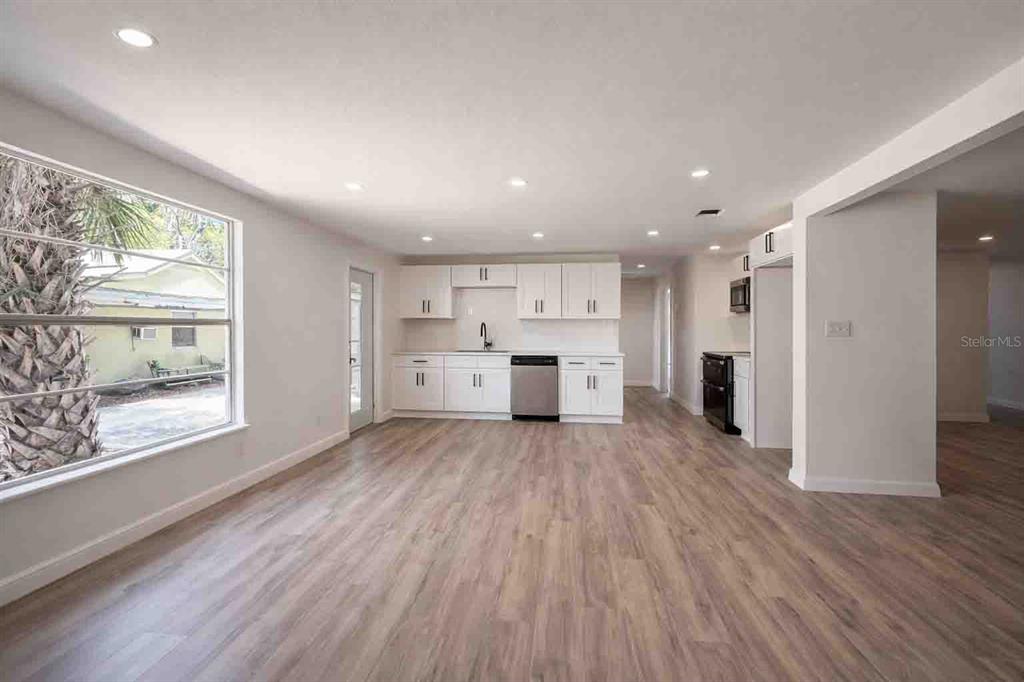 An open-concept kitchen and living area features white cabinets, stainless appliances, and wood-look flooring — 502 NW CRYSTAL STREET, CRYSTAL RIVER, FL