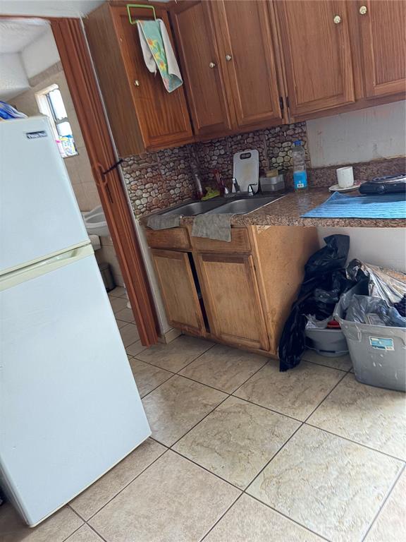 A kitchen features wood cabinets, a double sink, a white refrigerator, and tiled flooring — 1311 WOODMAN WAY, ORLANDO, FL