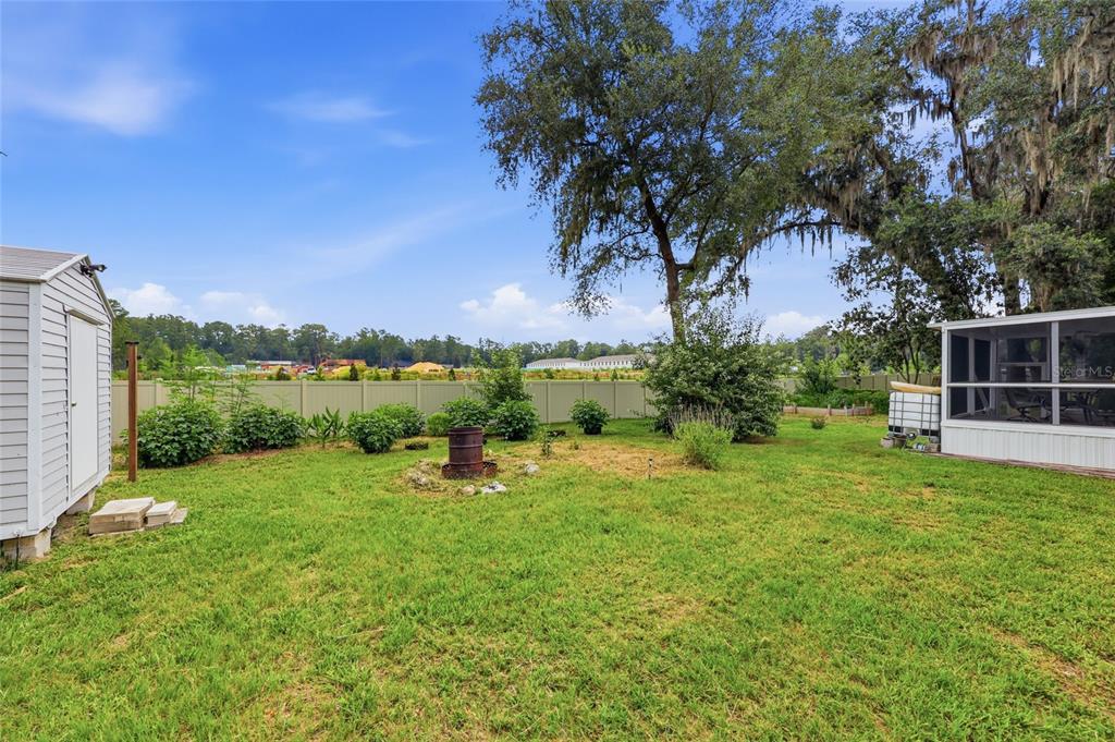 A grassy backyard features a storage shed, a screened-in porch, and a tall tree — 7014 SW 49TH PLACE, GAINESVILLE, FL