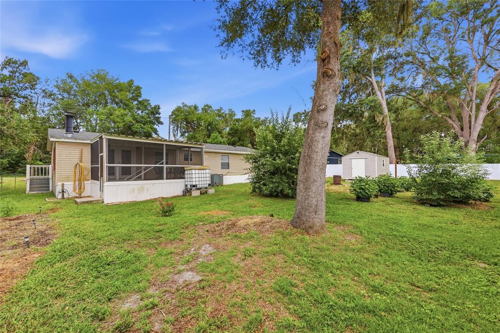 A backyard view of a house with a screened-in porch, a shed, and mature trees — 7014 SW 49TH PLACE, GAINESVILLE, FL