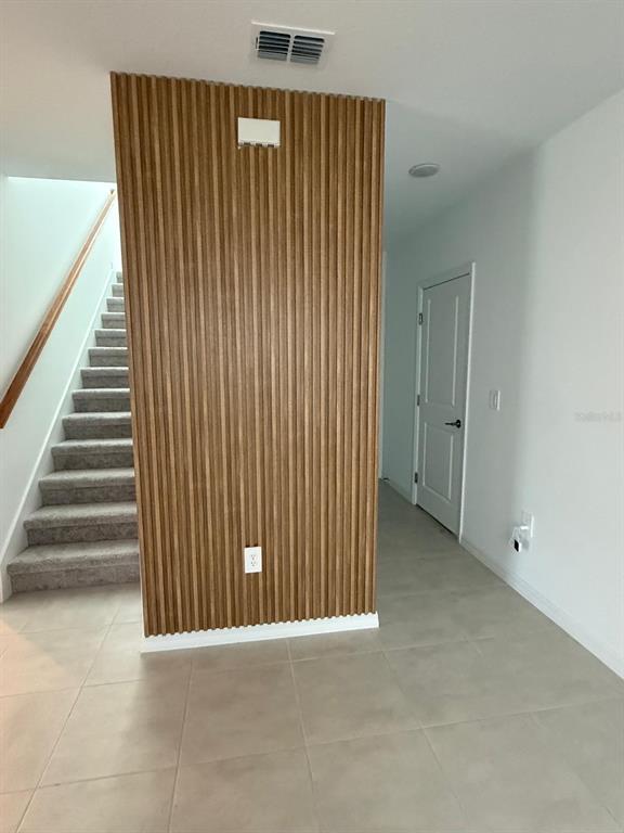 A wooden slat accent wall stands in a hallway next to a carpeted staircase — 424 WAYLAND DRIVE, HAINES CITY, FL