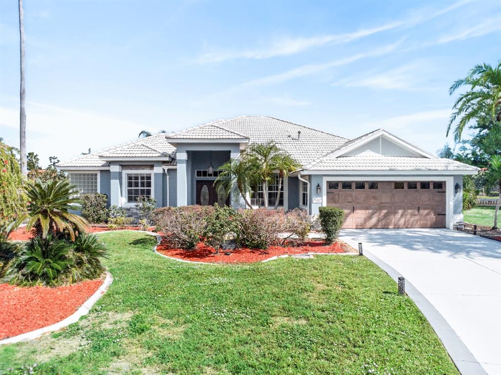 A single-story house with a tiled roof, a two-car garage, and a landscaped front yard — 6119 9TH AVENUE CIRCLE NE, BRADENTON, FL
