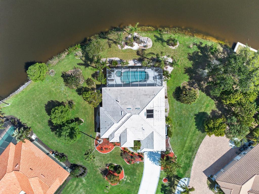 An aerial view shows a house with a screened pool, large yard, and waterfront access — 6119 9TH AVENUE CIRCLE NE, BRADENTON, FL