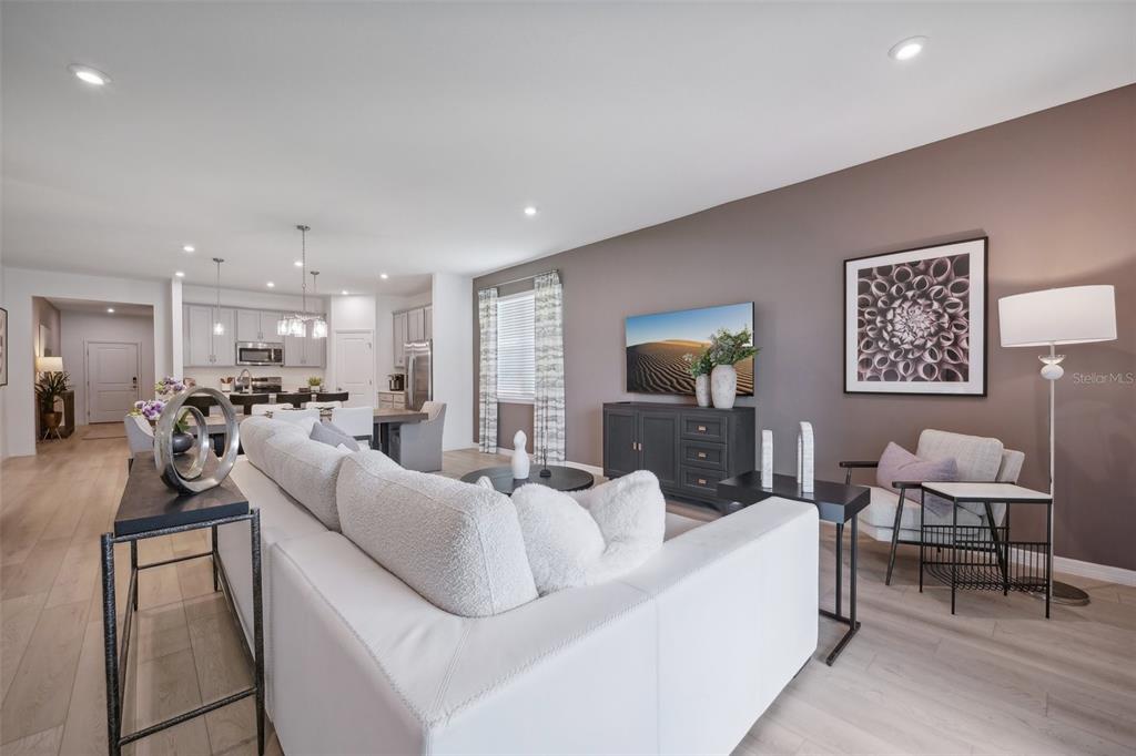 A modern living room with a white sofa, dark media console, and an open kitchen — 1709 FLAG STREET, HAINES CITY, FL