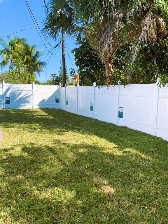A white vinyl privacy fence encloses a grassy backyard with palm trees under a blue sky — 320 NW 4th Avenue # 3, Deerfield Beach FL 33441, DEERFIELD BEACH, FL
