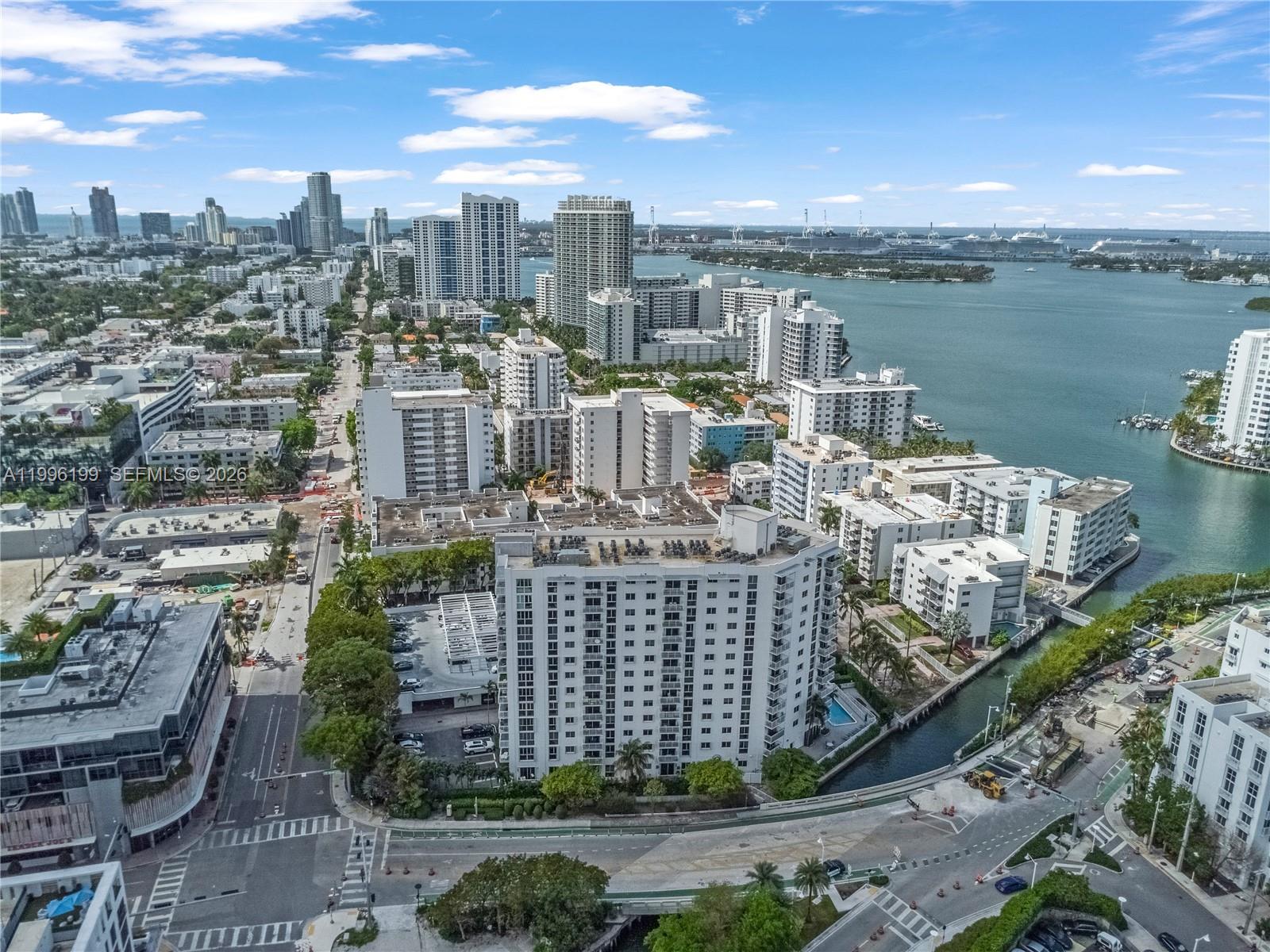 An aerial view shows a high-rise residential building surrounded by urban development and a waterway — 1688 West Ave # 408, Miami Beach FL 33139, MIAMI BEACH, FL