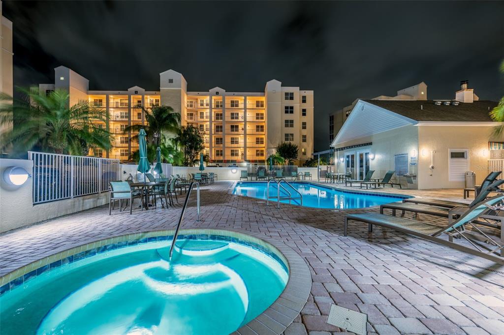 A night view of a swimming pool and hot tub on a paved patio — 1200 COUNTRY CLUB DRIVE UNIT 1206, LARGO, FL