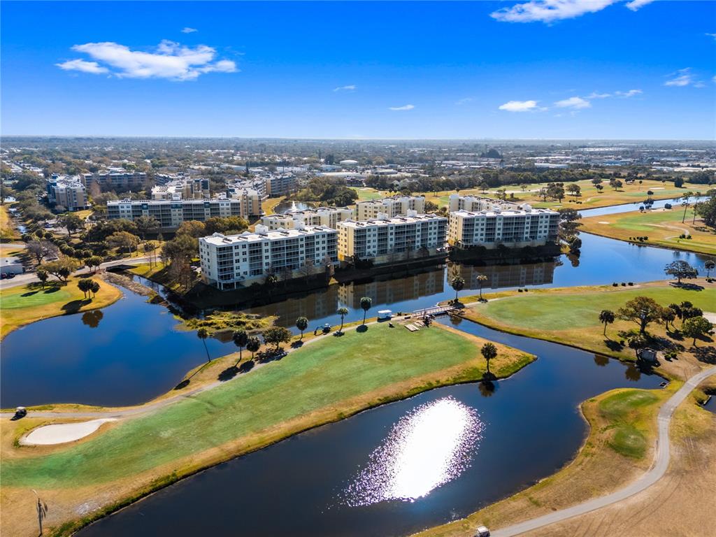 An aerial view shows multi-story apartment buildings situated along a golf course and water — 1200 COUNTRY CLUB DRIVE UNIT 1206, LARGO, FL