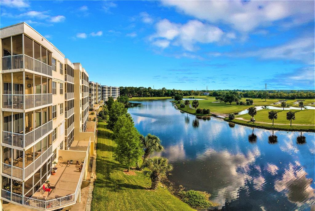 An exterior view of a multi-story apartment building overlooking a lake and golf course — 1200 COUNTRY CLUB DRIVE UNIT 1206, LARGO, FL