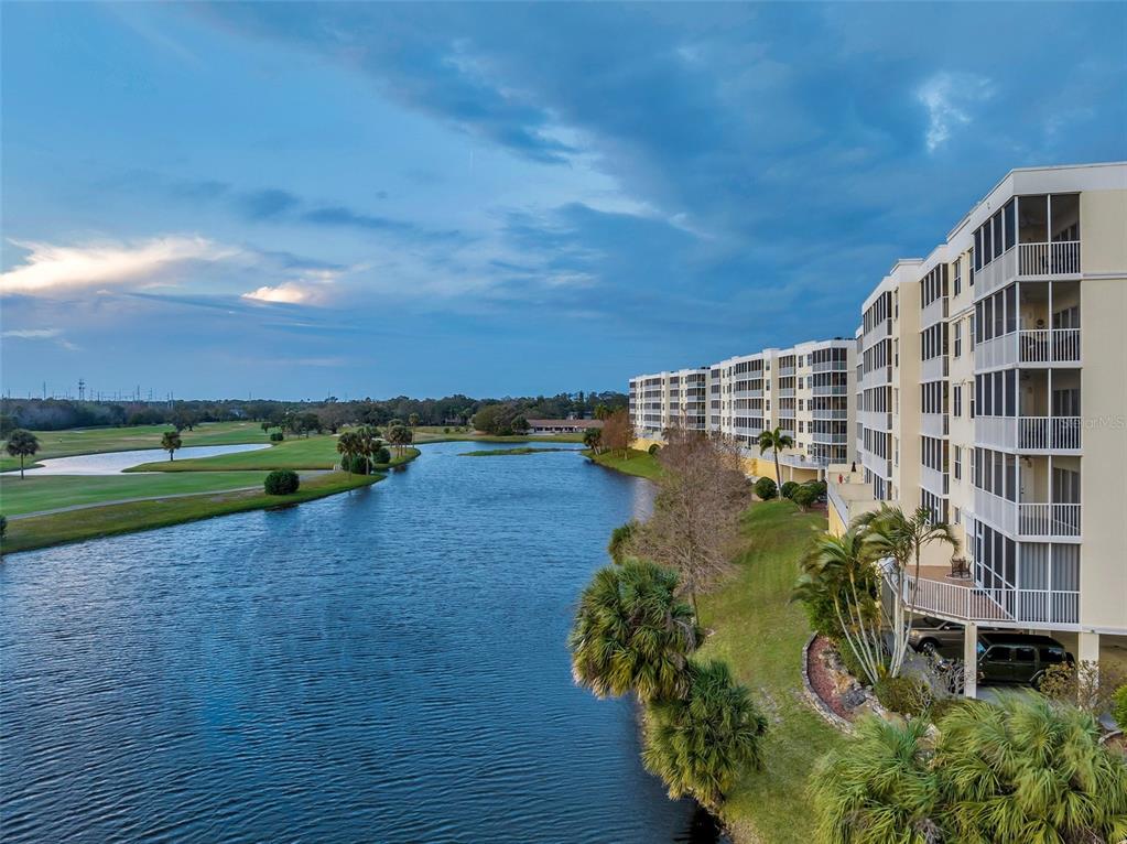 An exterior view of a multi-story apartment building overlooking a lake and golf course — 1200 COUNTRY CLUB DRIVE UNIT 1206, LARGO, FL