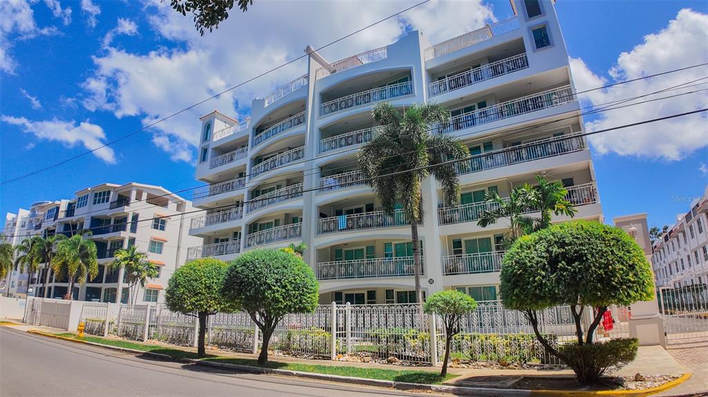A multi-story apartment building with balconies and palm trees behind a decorative metal fence — PR-115 ENSENADA WARD RINCON WAVE VIEW UNIT 1B, RINCON, PR