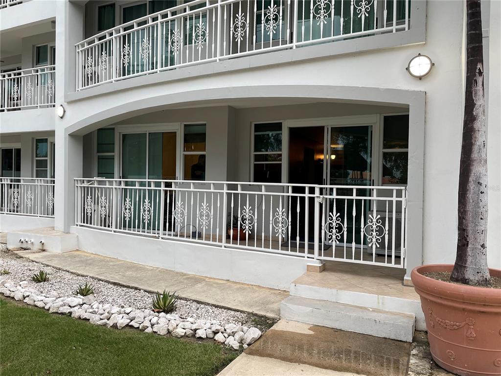A ground-floor patio with white metal railings and sliding glass doors leads to a lawn — PR-115 ENSENADA WARD RINCON WAVE VIEW UNIT 1B, RINCON, PR