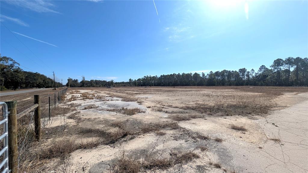 A wide, flat, cleared dirt lot is bordered by a fence and a line of trees — 13550 NW OLD FANNIN ROAD, CHIEFLAND, FL