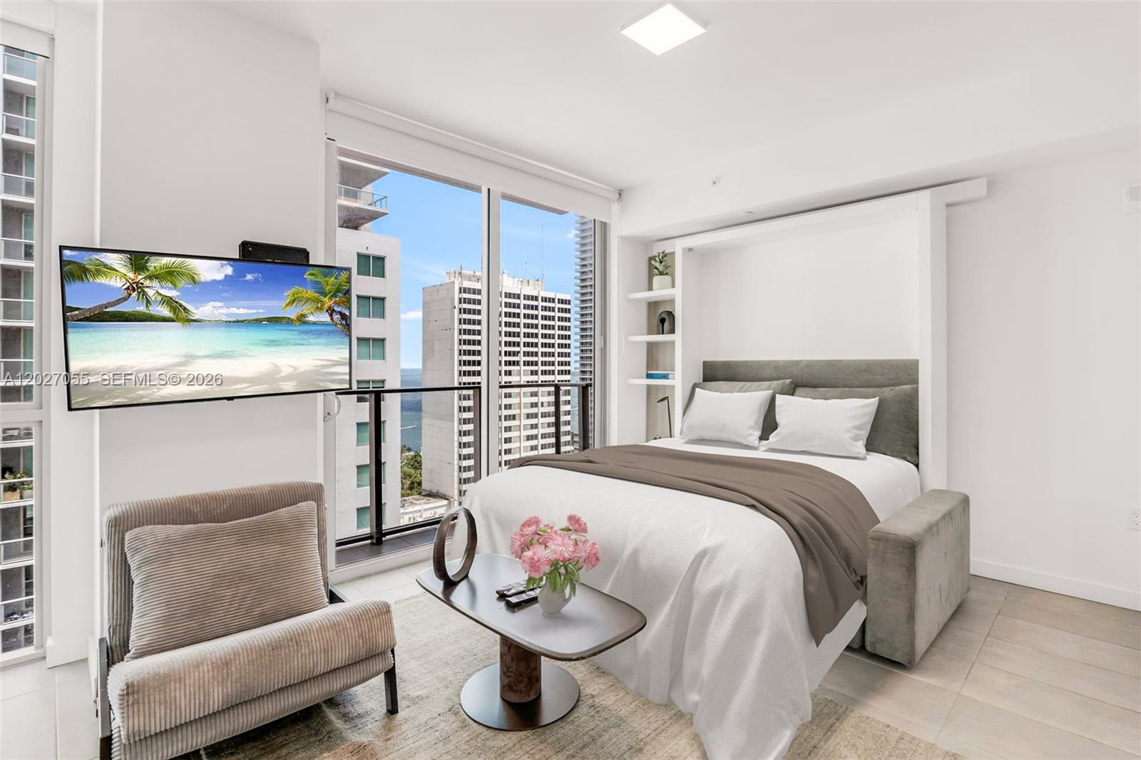 A modern studio apartment features a Murphy bed, a small coffee table, and city views — 227 NE 2nd St # 2611, Miami FL 33132, MIAMI, FL
