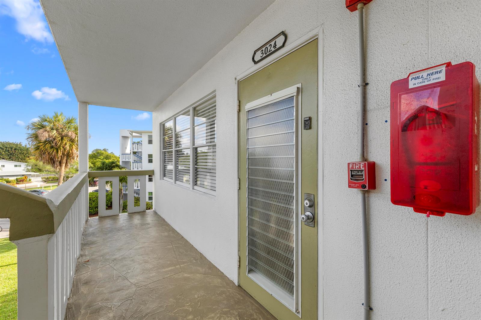 An exterior balcony features a green door with a louvered window and fire alarm equipment — 3024 Durham A, Deerfield Beach FL 33442, DEERFIELD BEACH, FL