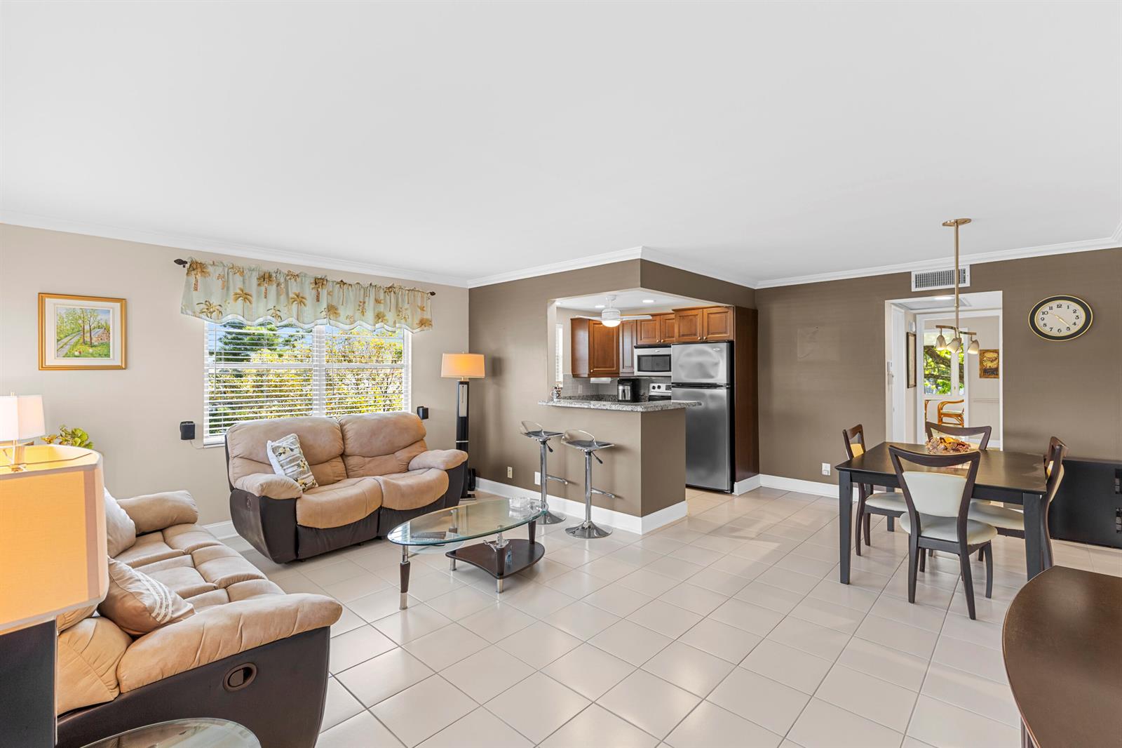 An open-concept living and dining area features tile flooring, a kitchen island, and neutral walls — 3024 Durham A, Deerfield Beach FL 33442, DEERFIELD BEACH, FL