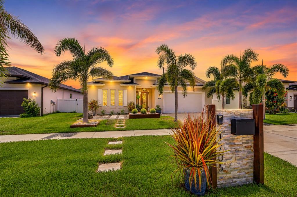 A single-story house with a stone mailbox, palm trees, and a sunset sky in front — 1706 W LOUISIANA AVENUE, TAMPA, FL