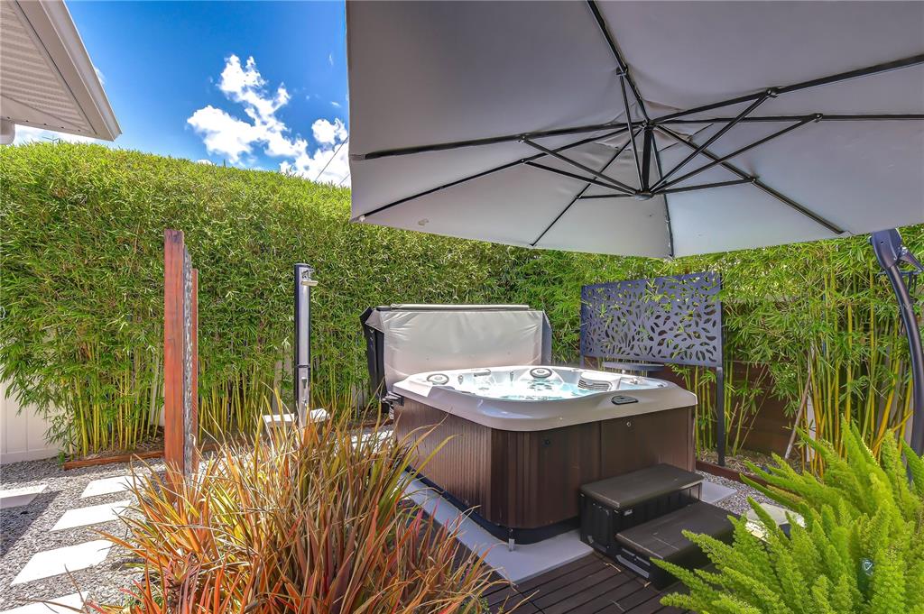 A hot tub sits on a wooden deck under a large umbrella in a backyard — 1706 W LOUISIANA AVENUE, TAMPA, FL