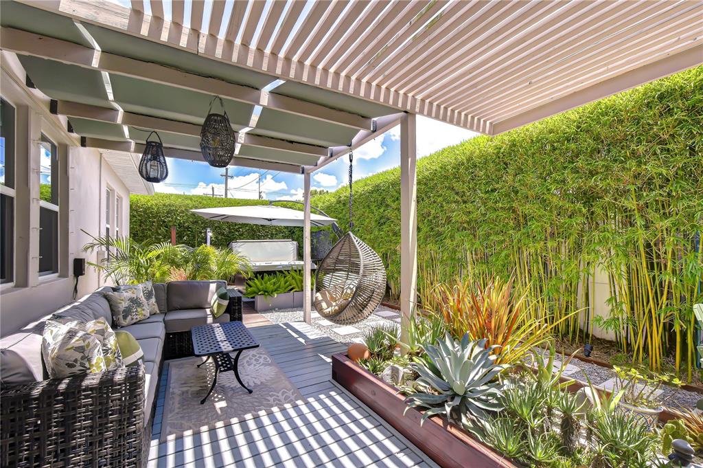 A patio features a gray sectional sofa, a hanging chair, and a wooden pergola roof — 1706 W LOUISIANA AVENUE, TAMPA, FL