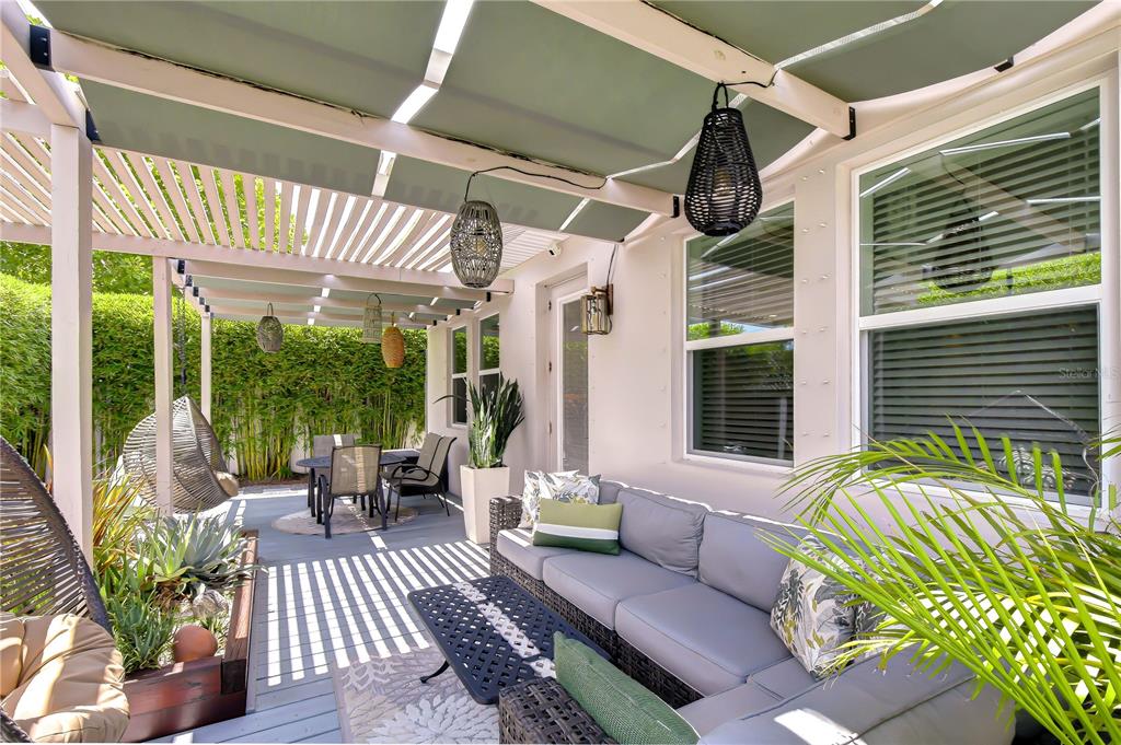A covered outdoor patio features a gray sectional sofa, dining area, and hanging pendant lights — 1706 W LOUISIANA AVENUE, TAMPA, FL
