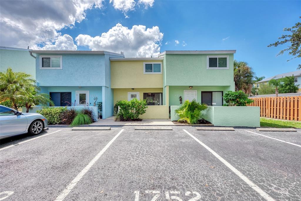 A row of three colorful townhouses features individual parking spaces in front of each unit — 1752 STICKNEY POINT ROAD UNIT 102, SARASOTA, FL
