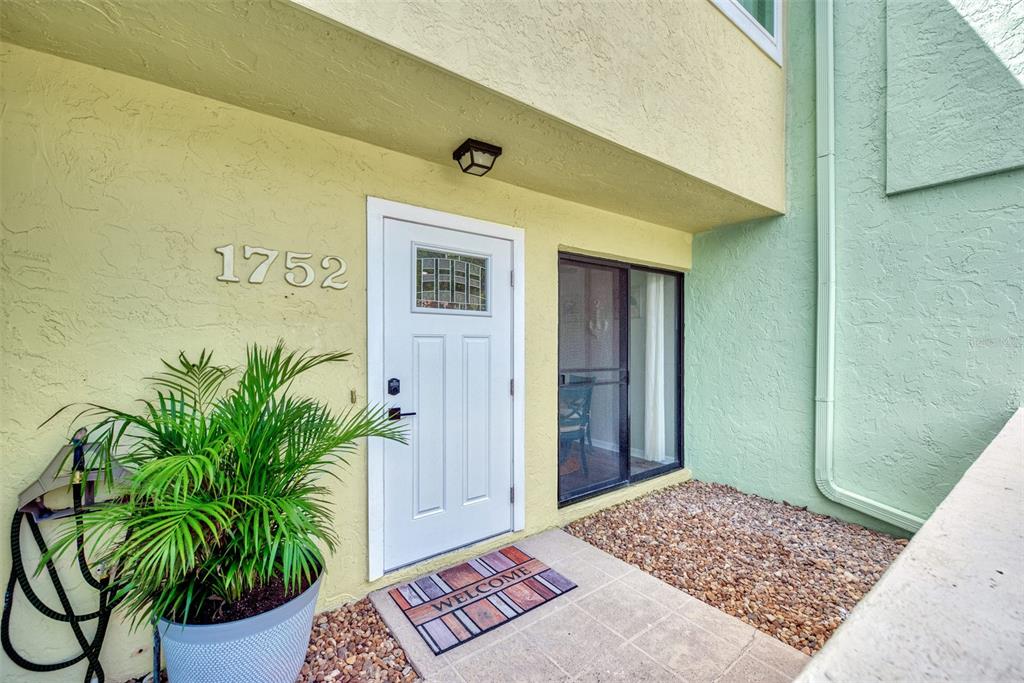The exterior entrance features a white door, a potted plant, and a gravel ground area — 1752 STICKNEY POINT ROAD UNIT 102, SARASOTA, FL
