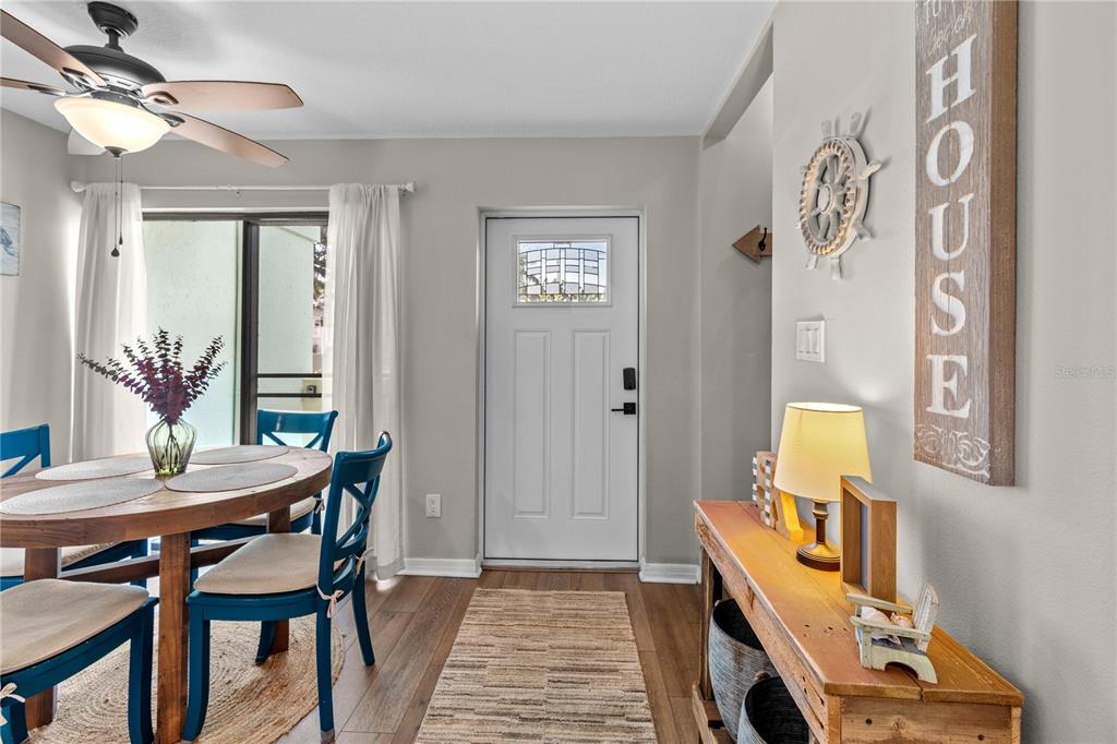 A dining area features a wooden table, blue chairs, a console table, and a front door — 1752 STICKNEY POINT ROAD UNIT 102, SARASOTA, FL