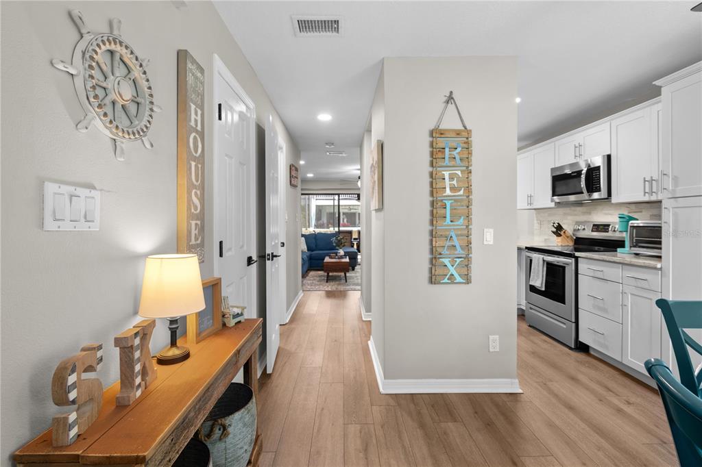 A hallway leads from a foyer with a console table toward a living area — 1752 STICKNEY POINT ROAD UNIT 102, SARASOTA, FL