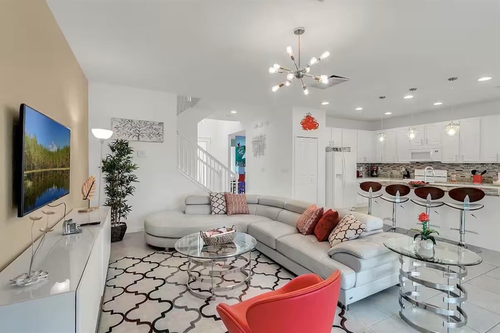 An open-concept living room features a white sectional sofa, a glass coffee table, and a kitchen — 2669 CALISTOGA AVENUE, KISSIMMEE, FL