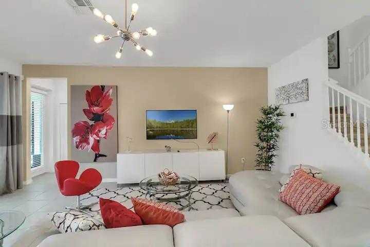 A living room features a white sectional sofa, a red accent chair, and a television — 2669 CALISTOGA AVENUE, KISSIMMEE, FL