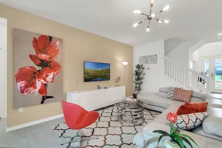 A living room features a white sectional sofa, a red accent chair, and a television — 2669 CALISTOGA AVENUE, KISSIMMEE, FL