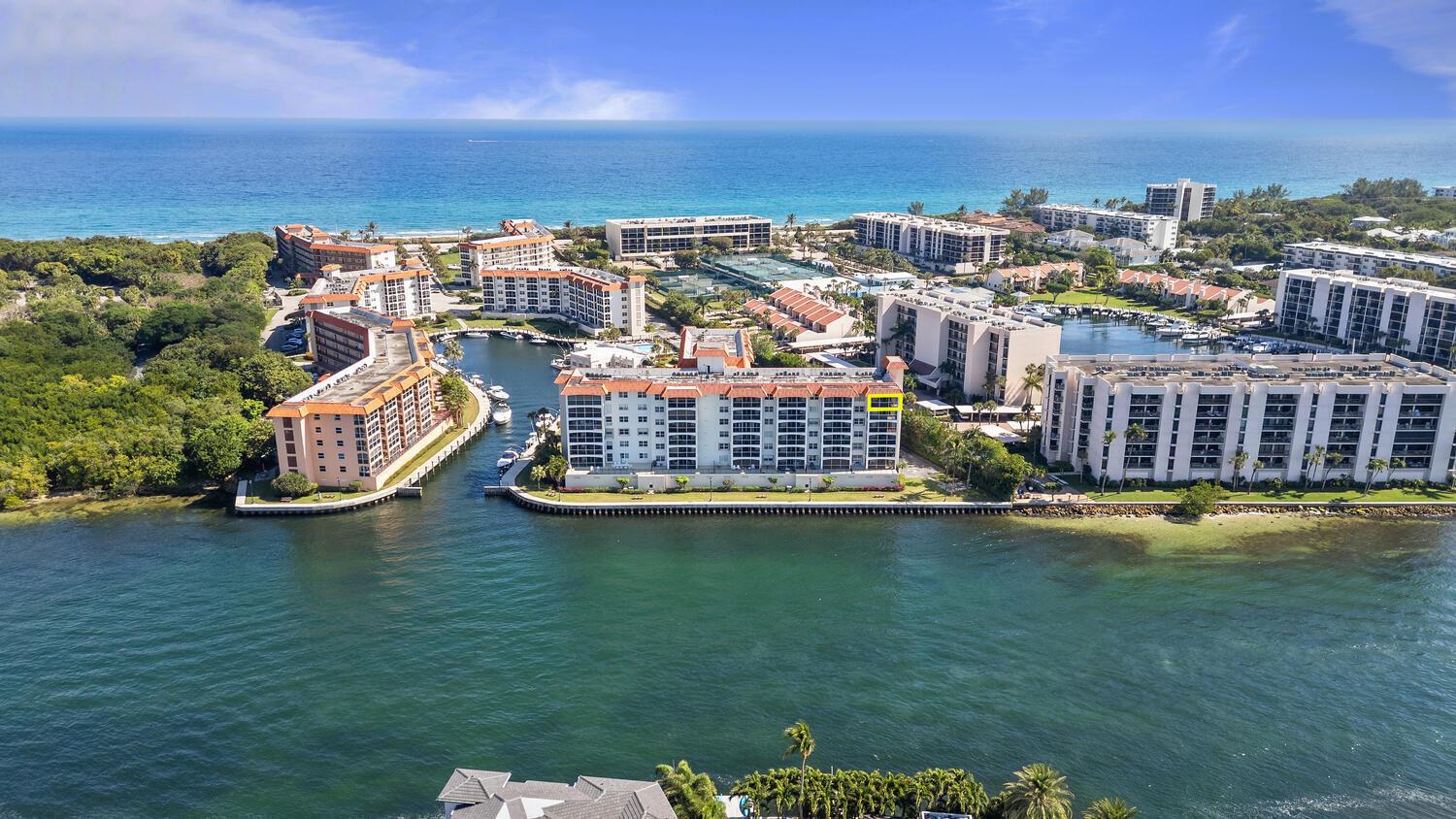 An aerial view shows multiple waterfront apartment buildings surrounded by lush greenery and the ocean — 2871 N Ocean Boulevard # V443, Boca Raton FL 33431, BOCA RATON, FL