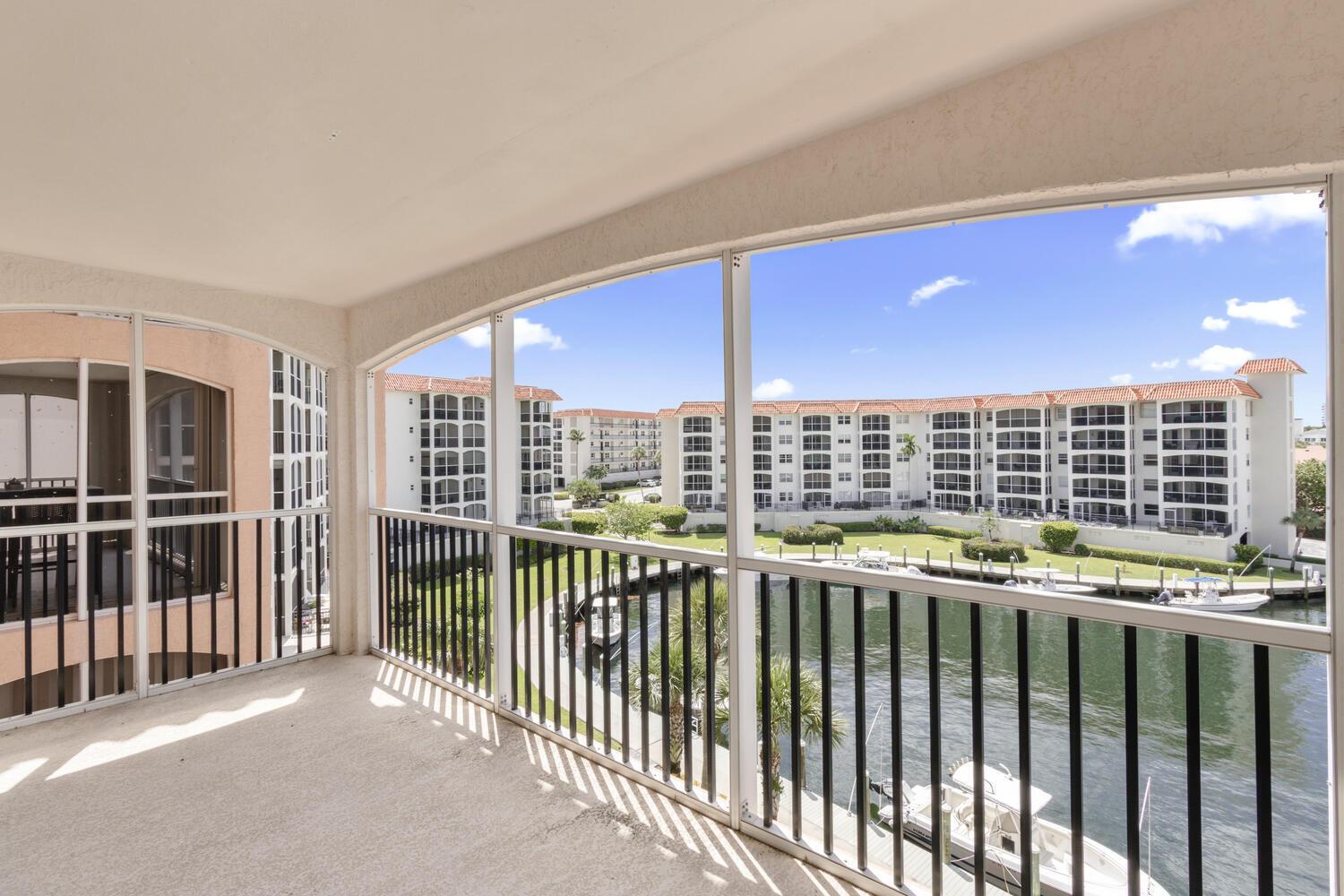 A screened-in balcony overlooks a canal, boat docks, and multi-story residential buildings — 2871 N Ocean Boulevard # V443, Boca Raton FL 33431, BOCA RATON, FL
