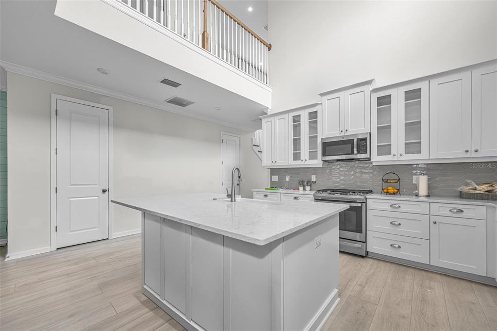 A kitchen with white cabinetry, a central island, and a lofted balcony overlooking the space — 13760 STEVENSON LANE, ODESSA, FL