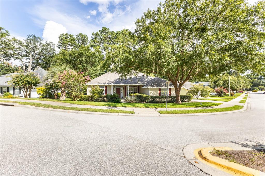A single-story house with beige siding and a red front door sits on a corner — 2429 NW 93RD STREET, GAINESVILLE, FL
