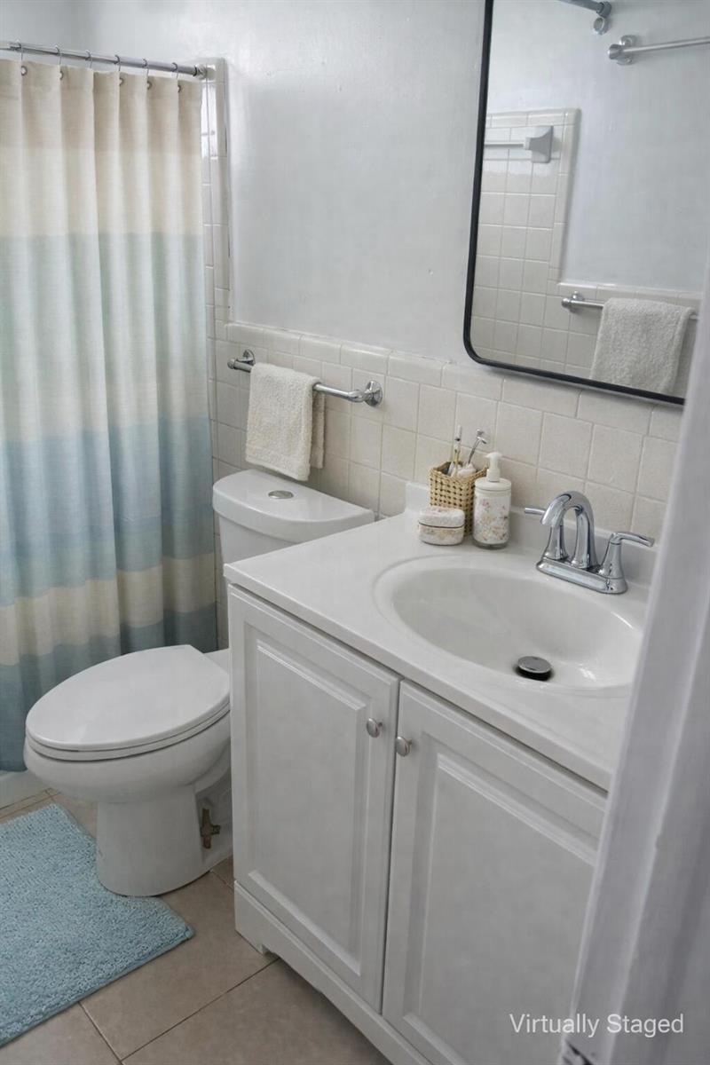 A bathroom with a white vanity, a toilet, and a blue and white shower curtain — FORT LAUDERDALE, FL